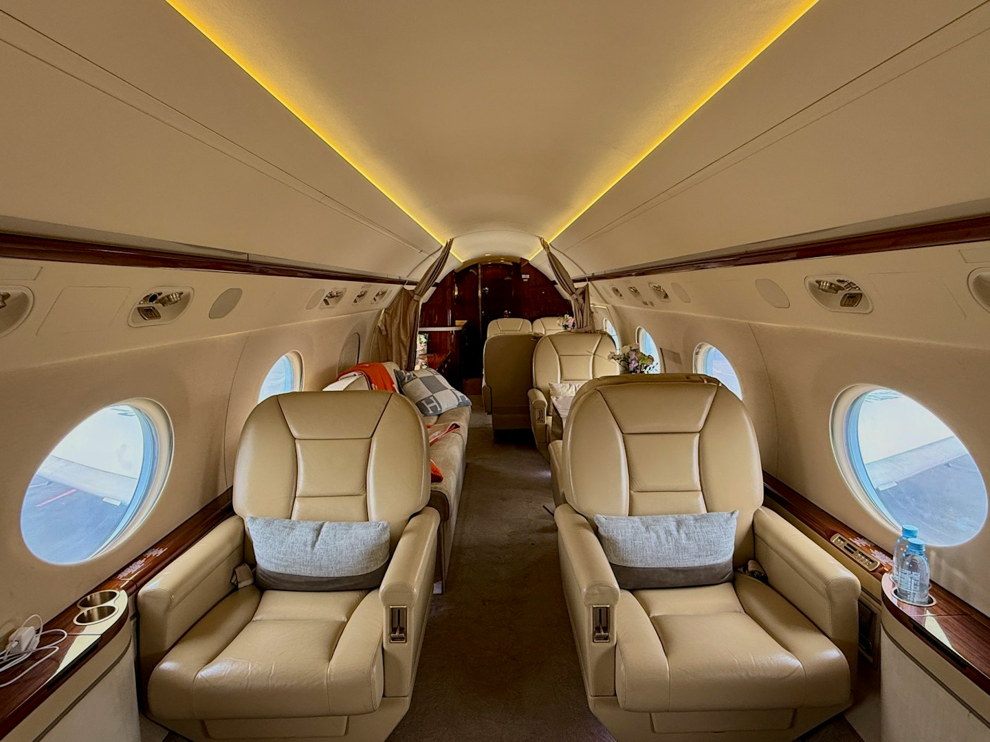 Beige leather seats arranged inside a private jet cabin.